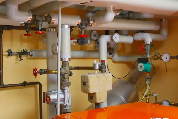 Water pipes, valves, pressure gauges and pumping equipment in a plant room