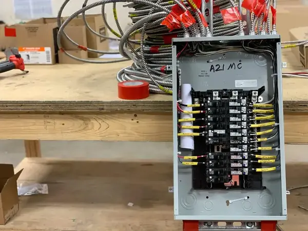 Open electrical panel with many flexible metal conduits and labeled breakers
